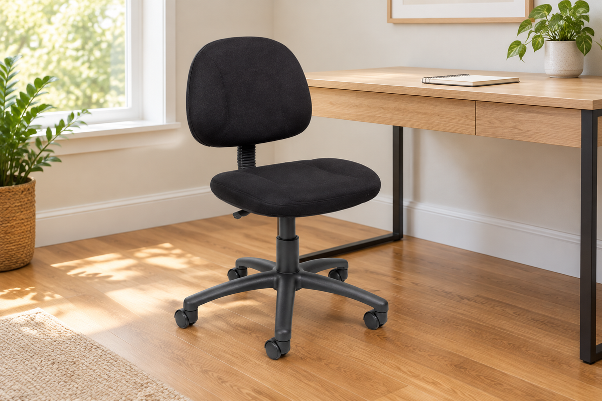 Black armless padded office chair beside a desk in a sunlit home workspace